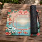 A square mahjong mat with flamingos, hibiscus flowers, palm leaves, and aqua water accents on a coral background with a scalloped edge.