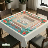 A square mahjong mat with flamingos, hibiscus flowers, palm leaves, and aqua water accents on a coral background with a scalloped edge.