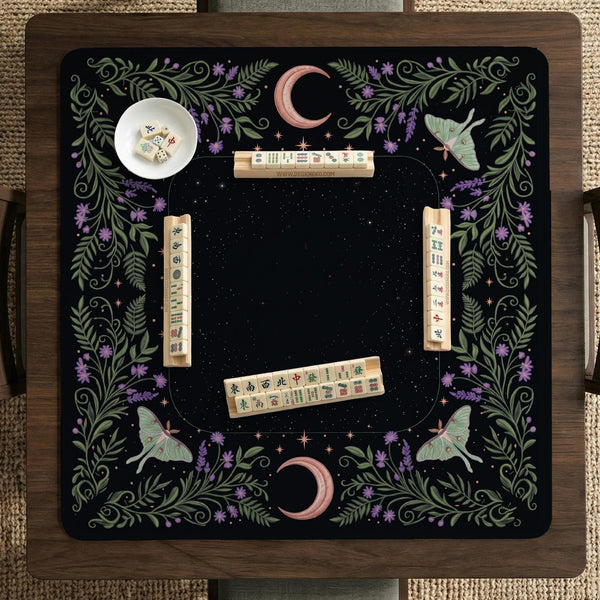 Black mahjong table mat with luna moths, purple flowers, soft green leaves, copper moons, and small star details.