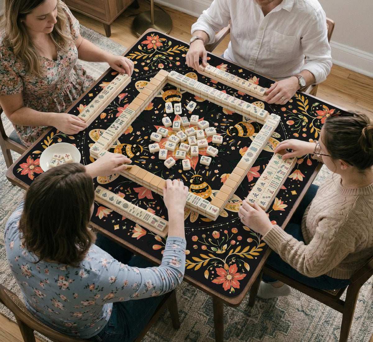 Black mahjong mat with a symmetrical botanical design, coral flowers, golden leaves, and small bees.