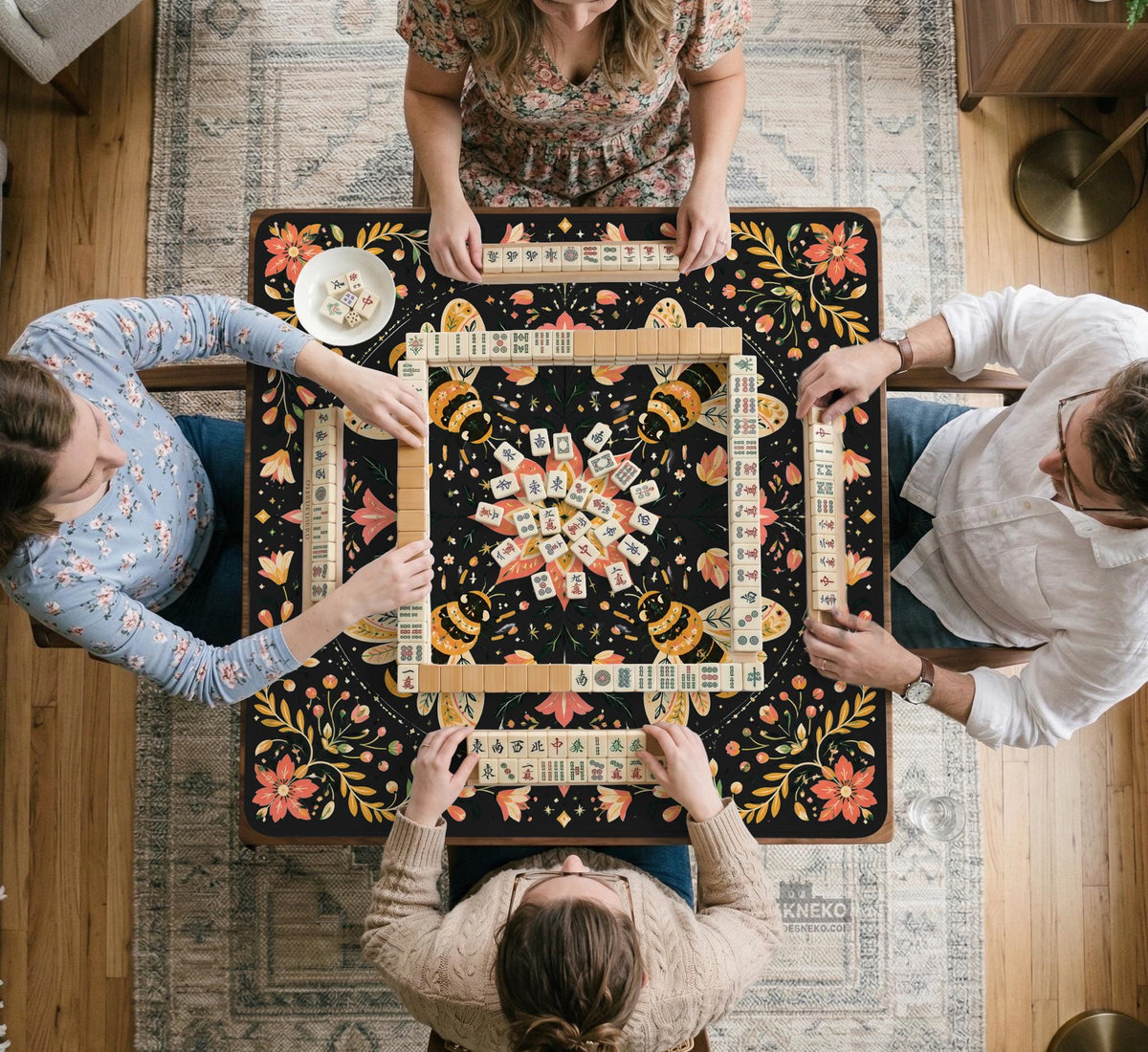 Black mahjong mat with a symmetrical botanical design, coral flowers, golden leaves, and small bees.