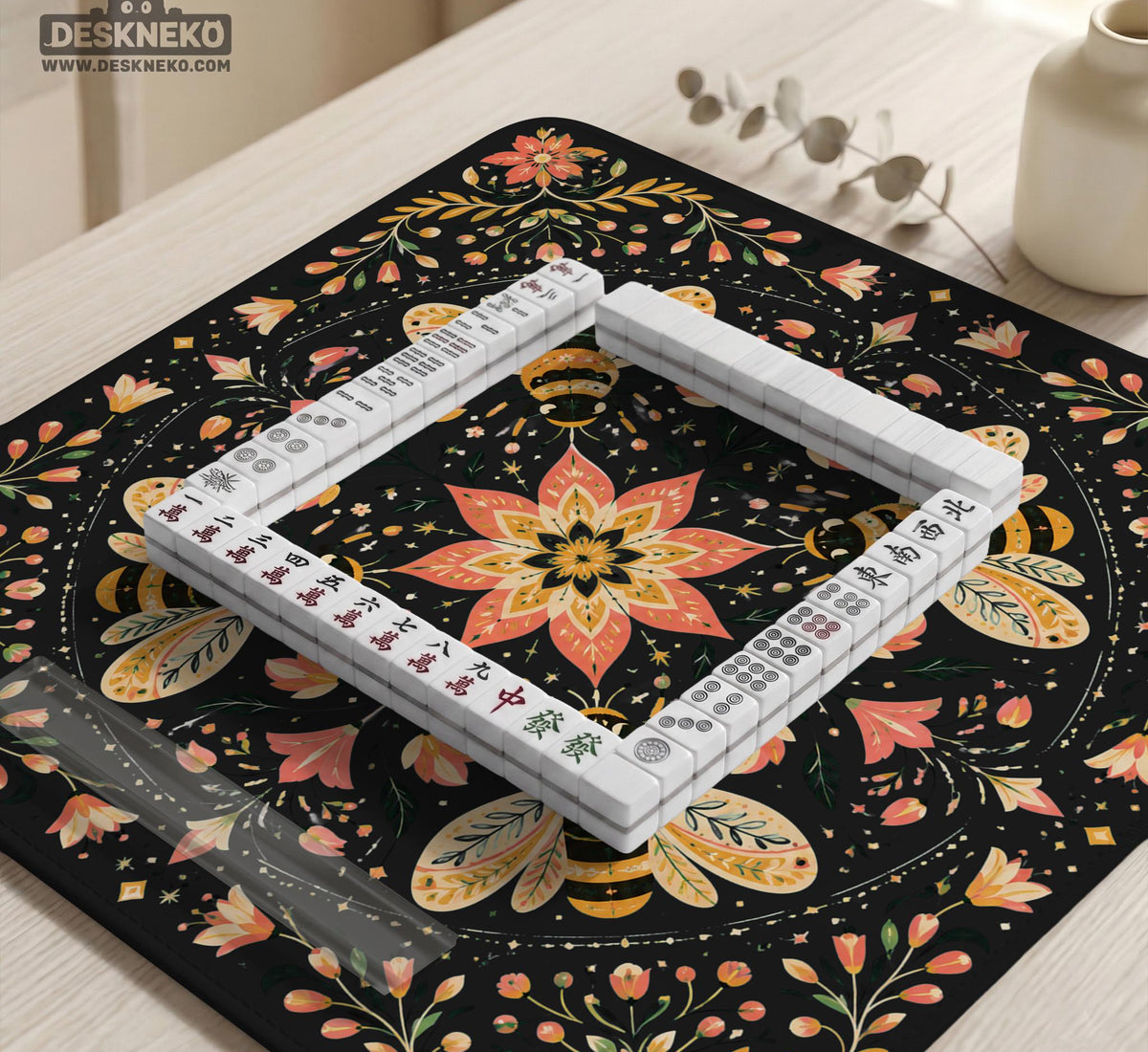 Black mahjong mat with a symmetrical botanical design, coral flowers, golden leaves, and small bees.