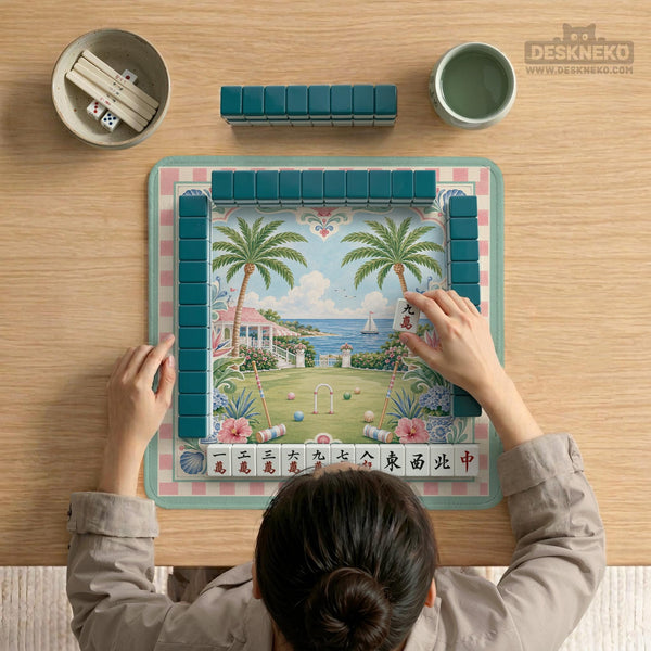 Pastel mahjong mat with a pink gingham border, seashells, hydrangea pots, palm trees, croquet details, and a coastal garden scene.
