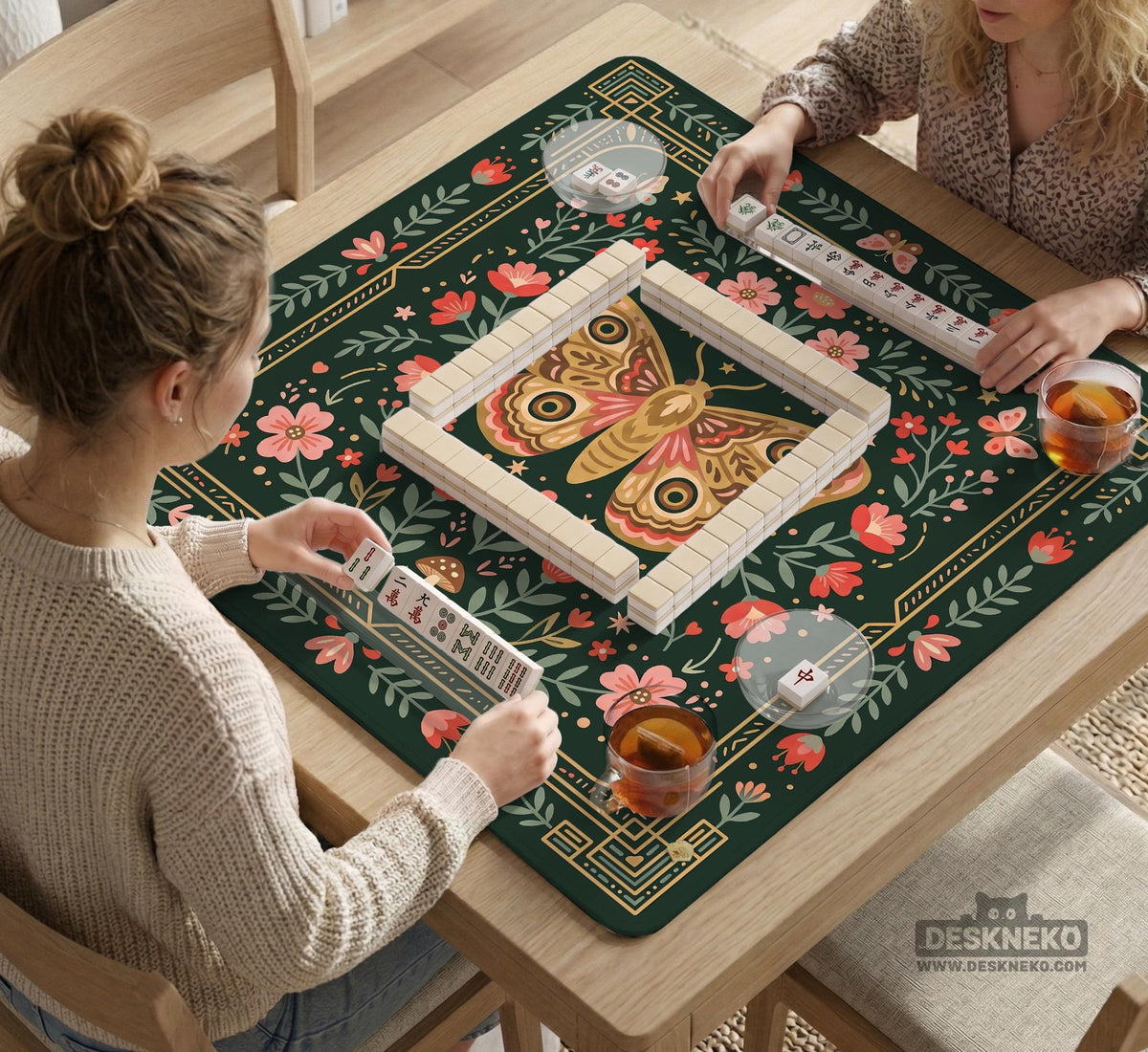 Dark green square mahjong mat with floral branches, small red blossoms, gold line details, and a large moth in the center.