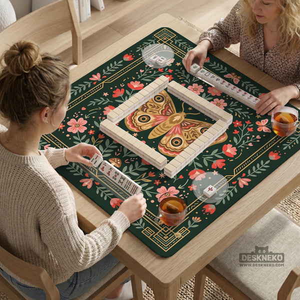 Dark green square mahjong mat with floral branches, small red blossoms, gold line details, and a large moth in the center.