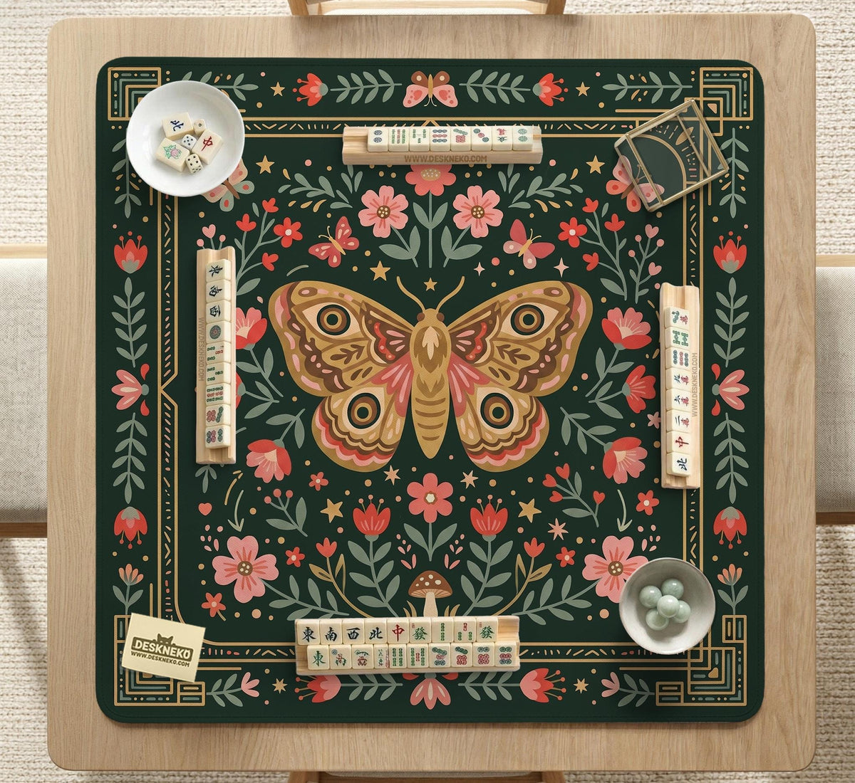 Dark green square mahjong mat with floral branches, small red blossoms, gold line details, and a large moth in the center.