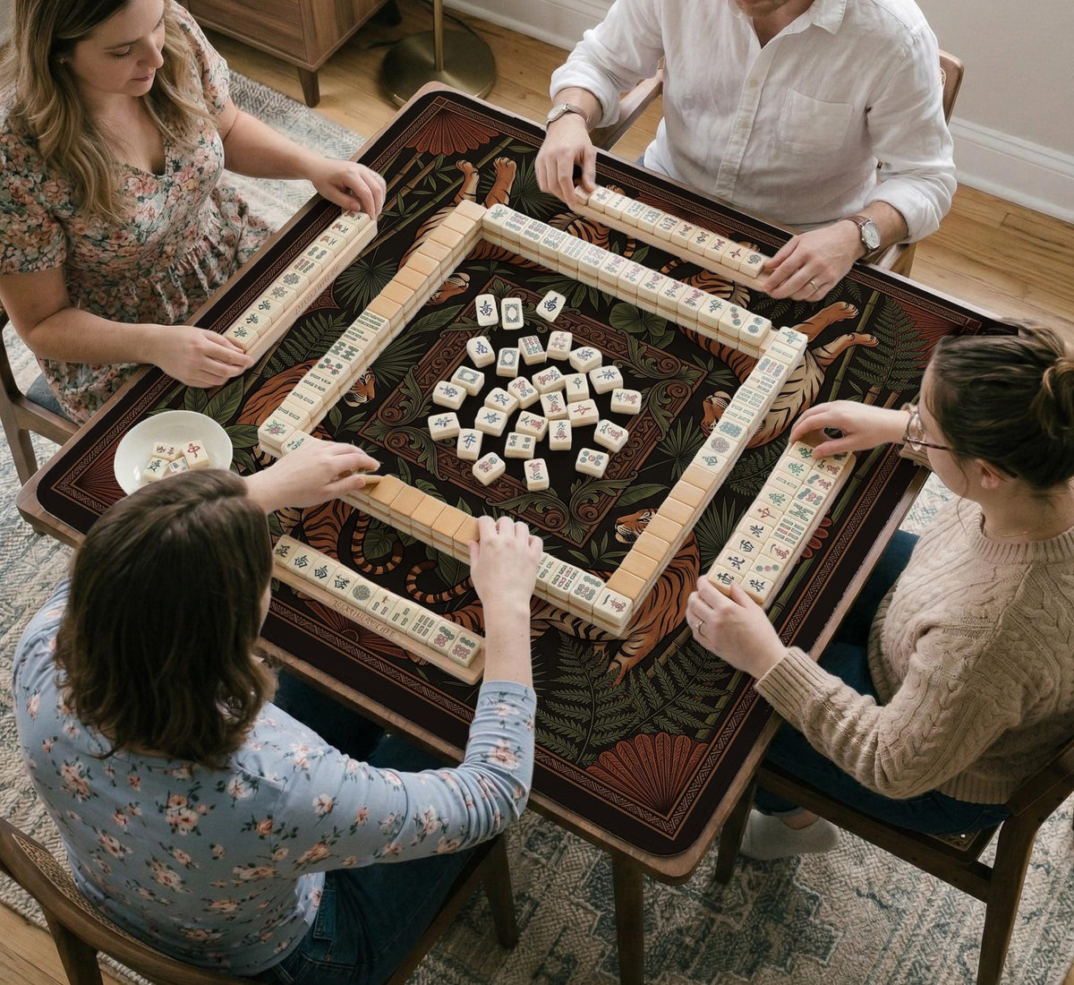 Black square mahjong mat with mirrored tiger faces, bamboo, dark tropical leaves, ornate border details, and orange accents.