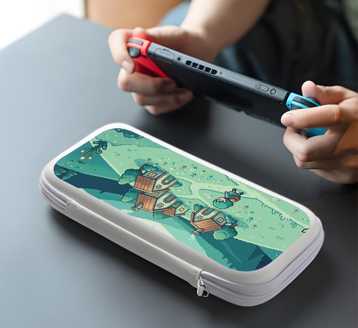 Teal carrying case with a pixel-style village scene, small houses, layered mountains, flowers, and a retro game-inspired landscape design.