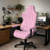 Soft pink floral chair cover shown on a gaming chair with a high back and armrests.