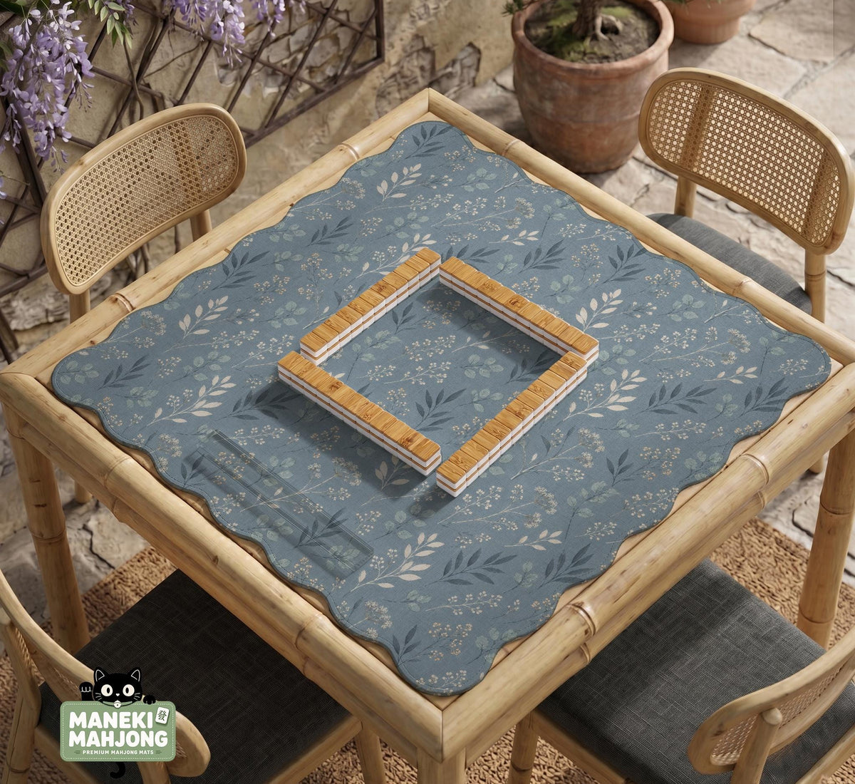Blue mahjong mat with a botanical floral pattern, pale leaves, and delicate stems on a dusty blue background.