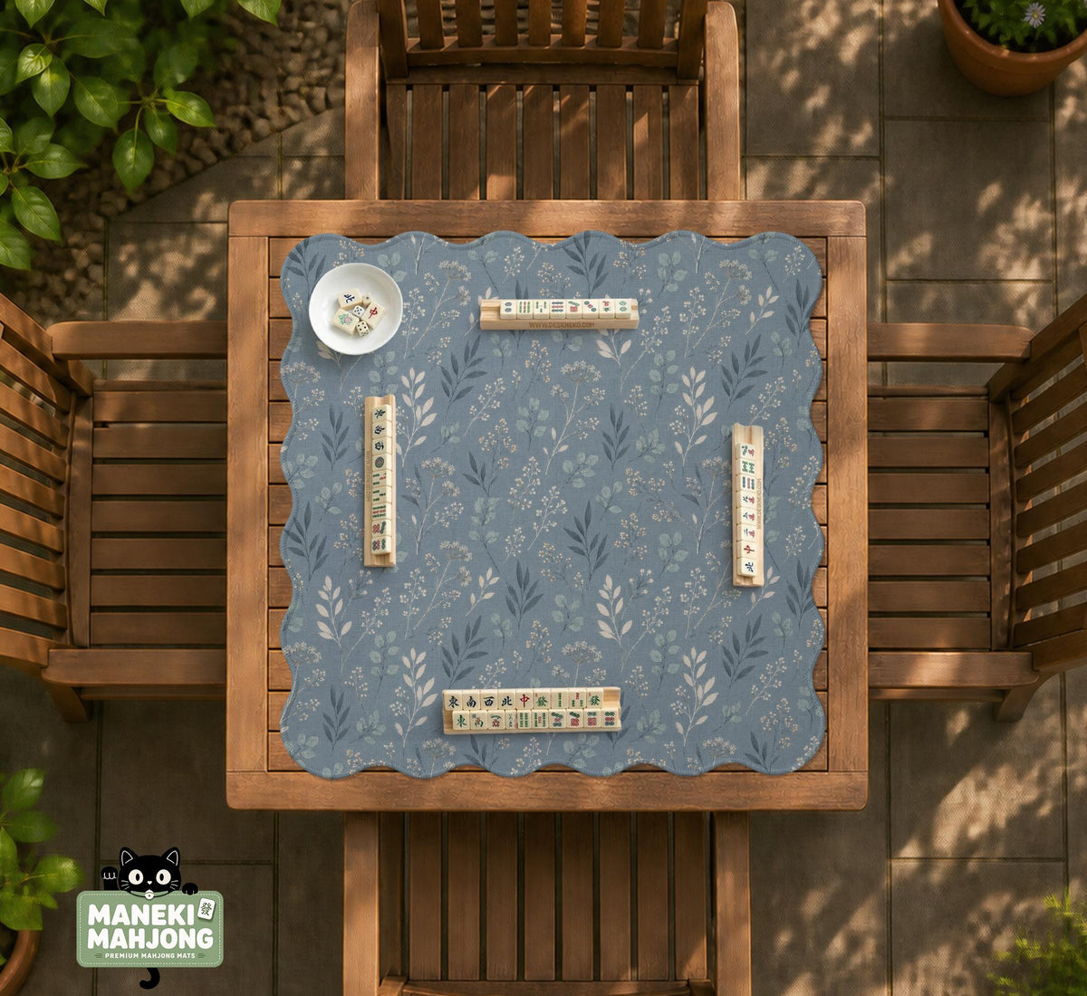 Blue mahjong mat with a botanical floral pattern, pale leaves, and delicate stems on a dusty blue background.