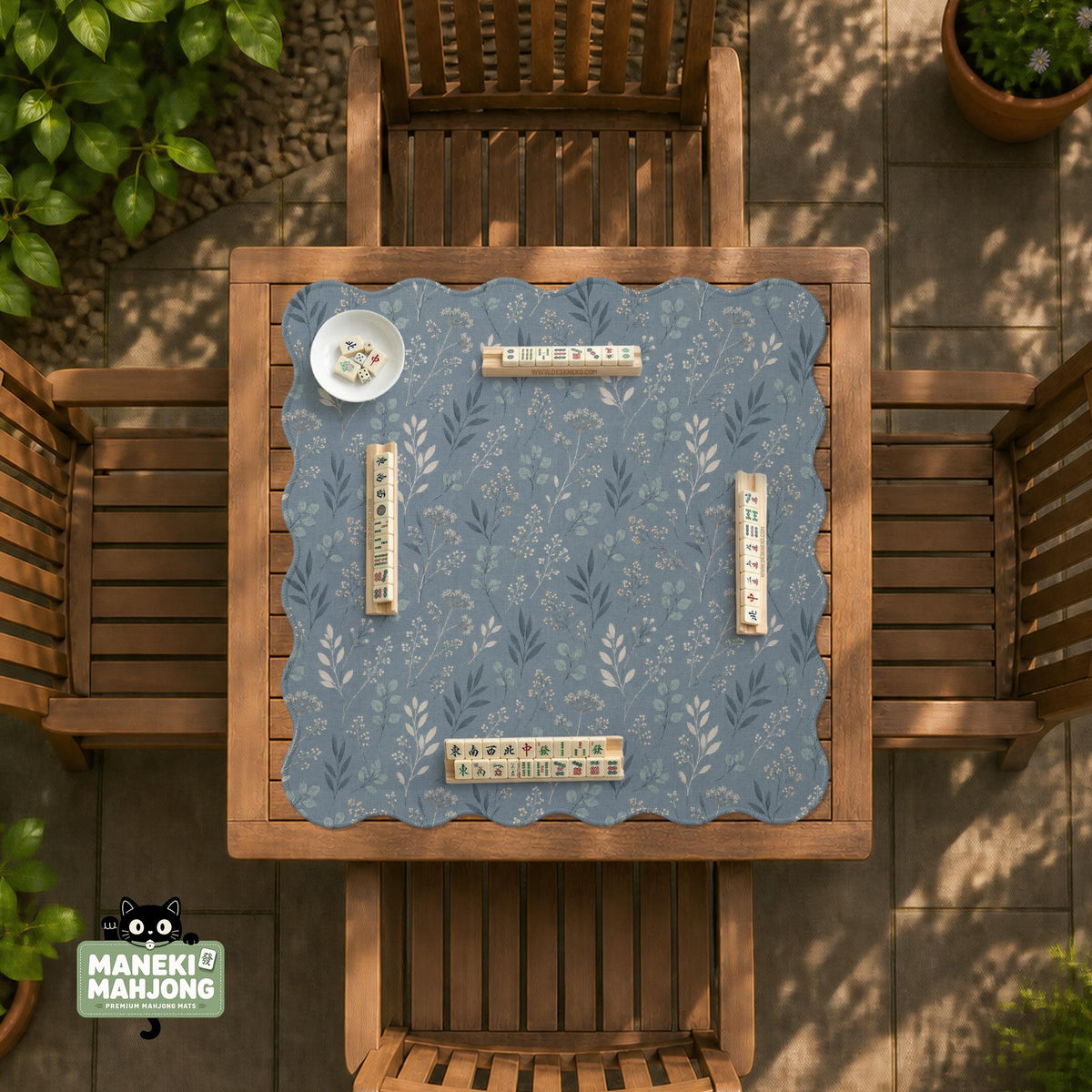 Blue mahjong mat with a botanical floral pattern, pale leaves, and delicate stems on a dusty blue background.