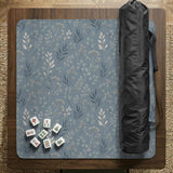 Blue mahjong mat with a botanical floral pattern, pale leaves, and delicate stems on a dusty blue background.