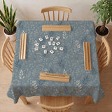 Blue mahjong mat with a botanical floral pattern, pale leaves, and delicate stems on a dusty blue background.