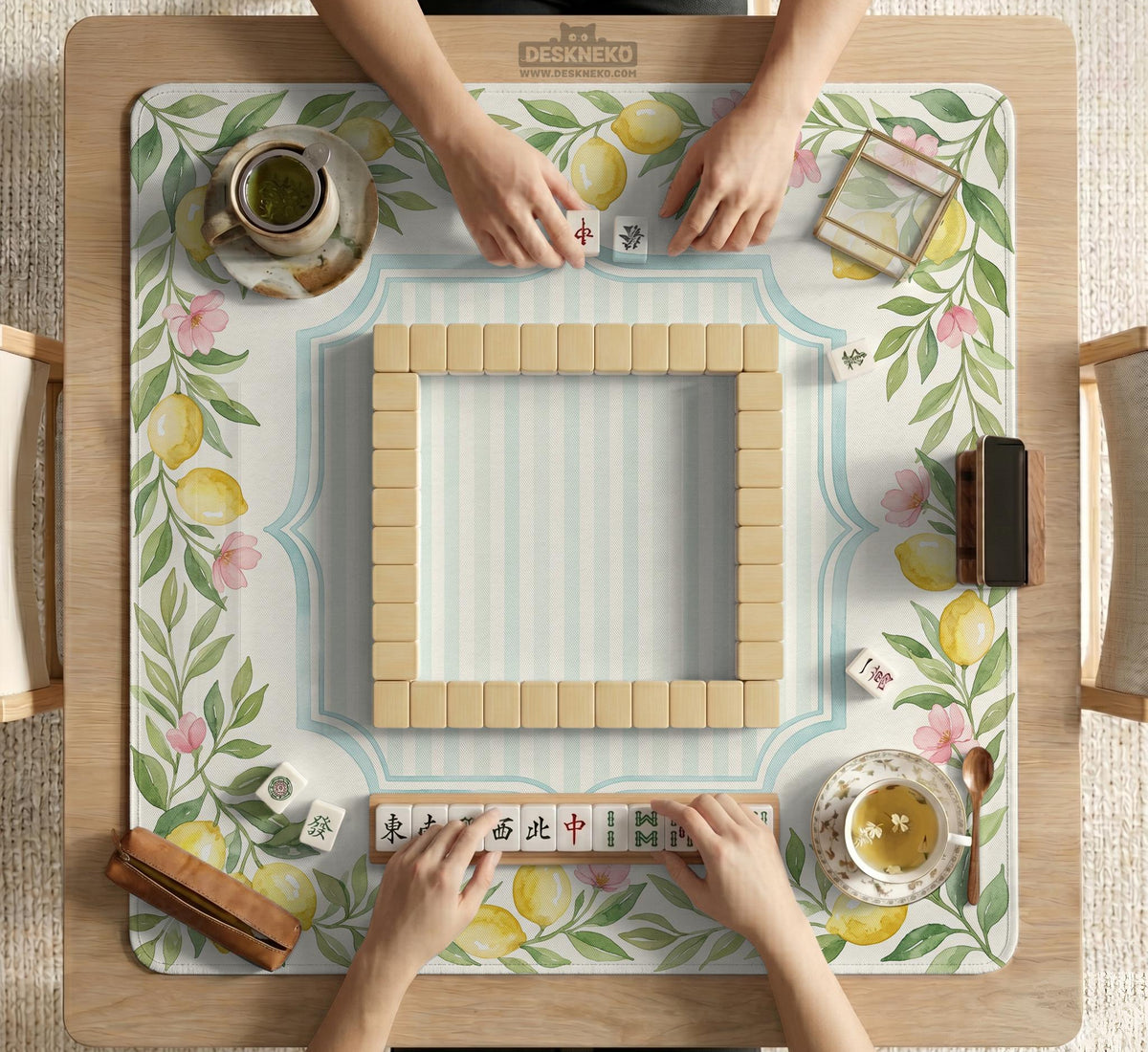 Square yellow mahjong mat with a citrus garden border, green vines, pink blossoms, aqua accents, and a plain center play area.