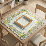 Square yellow mahjong mat with a citrus garden border, green vines, pink blossoms, aqua accents, and a plain center play area.