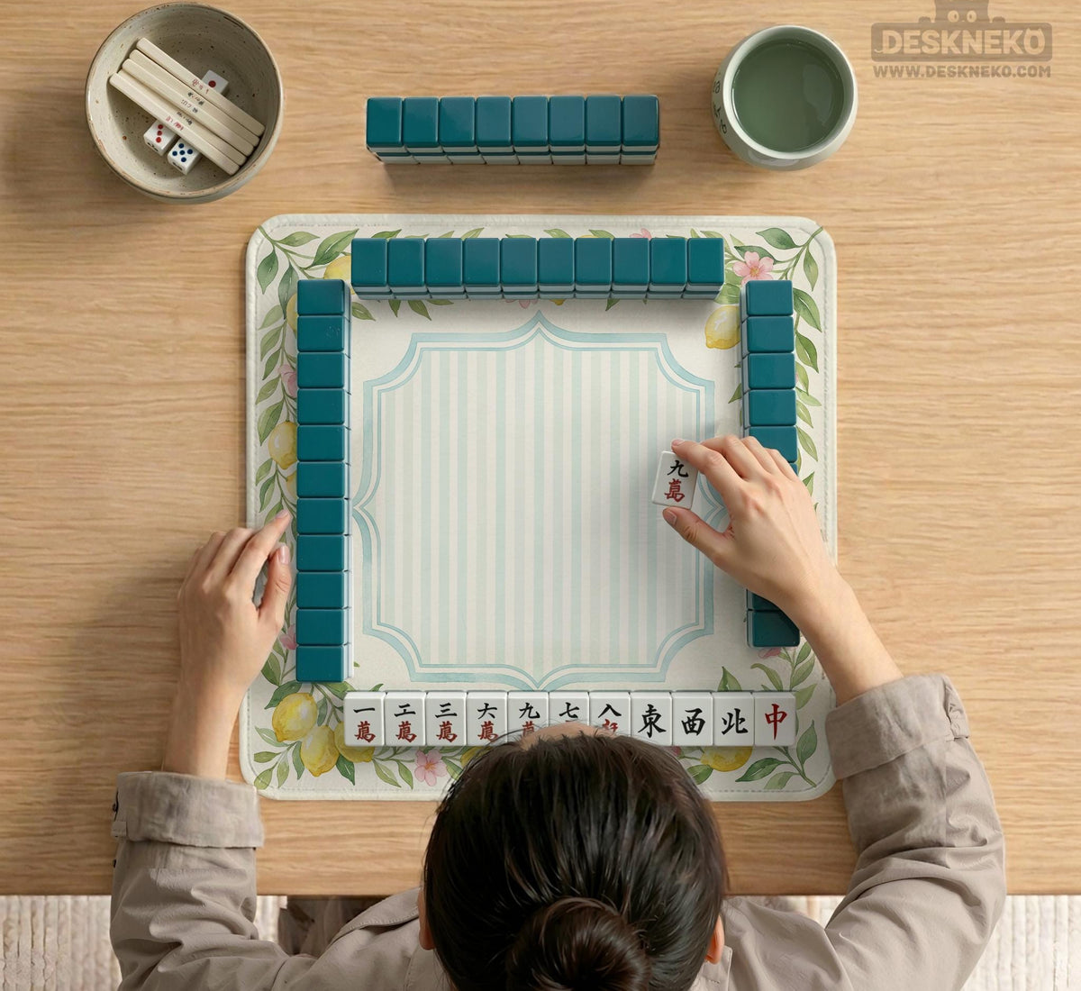Square yellow mahjong mat with a citrus garden border, green vines, pink blossoms, aqua accents, and a plain center play area.