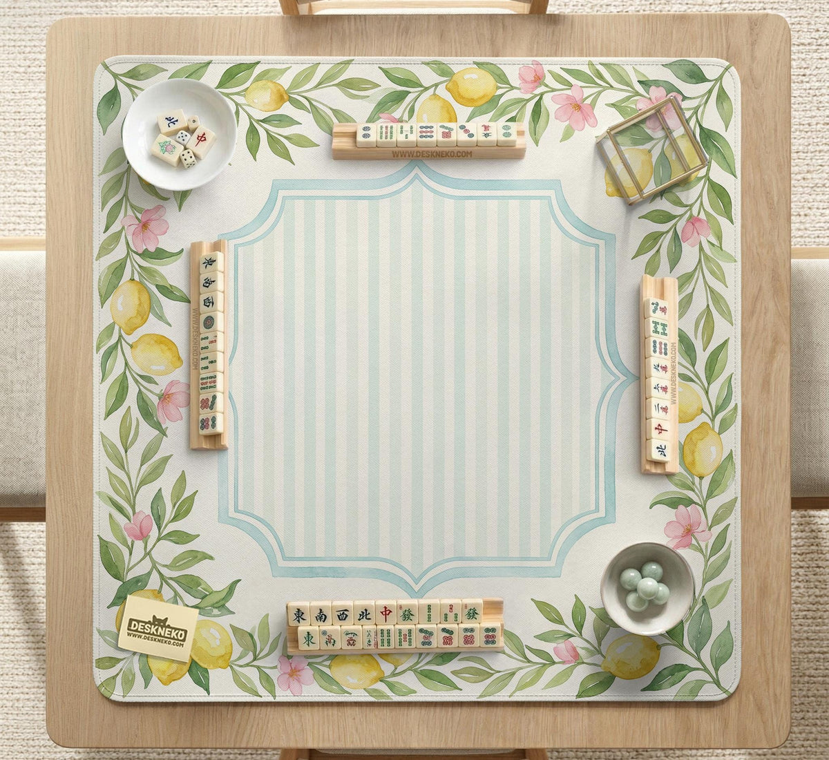 Square yellow mahjong mat with a citrus garden border, green vines, pink blossoms, aqua accents, and a plain center play area.