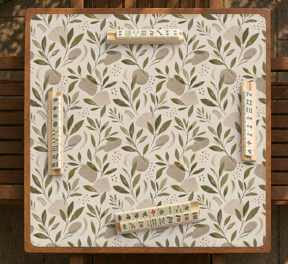 Green botanical mahjong mat with sage leaf and floral design and a scalloped edge.