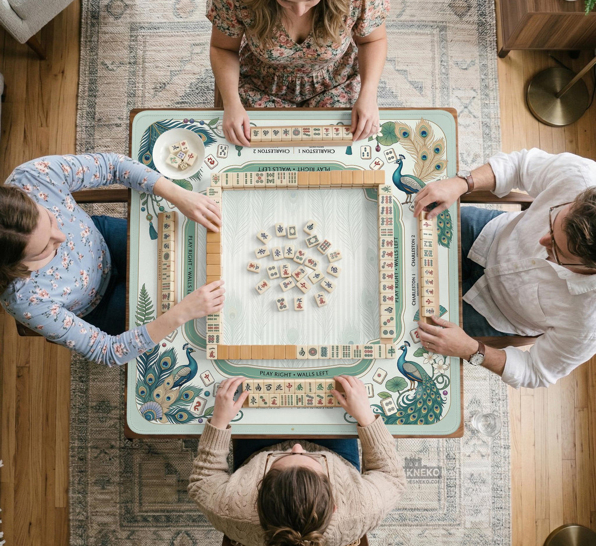 Teal square mahjong mat with peacock feathers, soft floral pattern, tassel details, and printed rule guide text in the center.