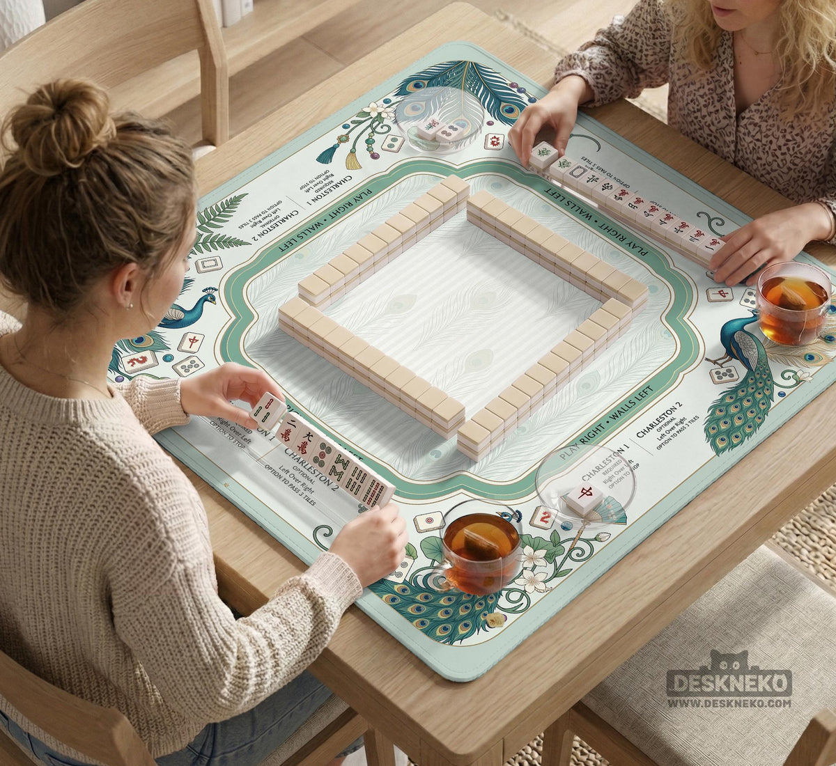 Teal square mahjong mat with peacock feathers, soft floral pattern, tassel details, and printed rule guide text in the center.