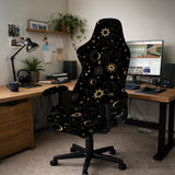 Black chair cover with gold moons, suns, stars, constellations, and line art printed across the fabric.