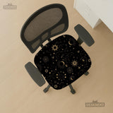 Black chair cover with gold moons, suns, stars, constellations, and line art printed across the fabric.