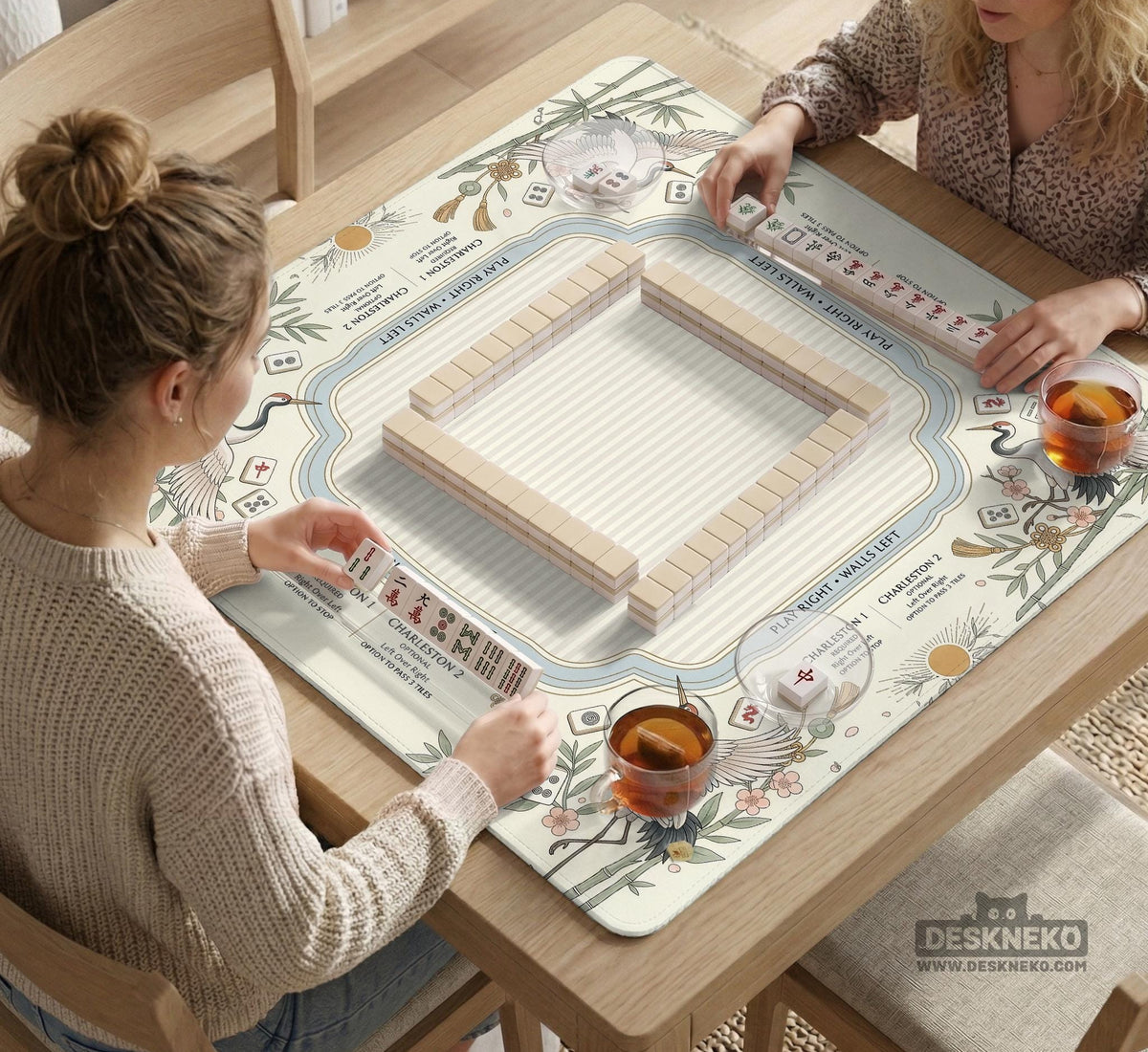 Beige square mahjong mat with a sage border, crane birds, bamboo, flowers, tile icons, and printed rules around a clean center play area.