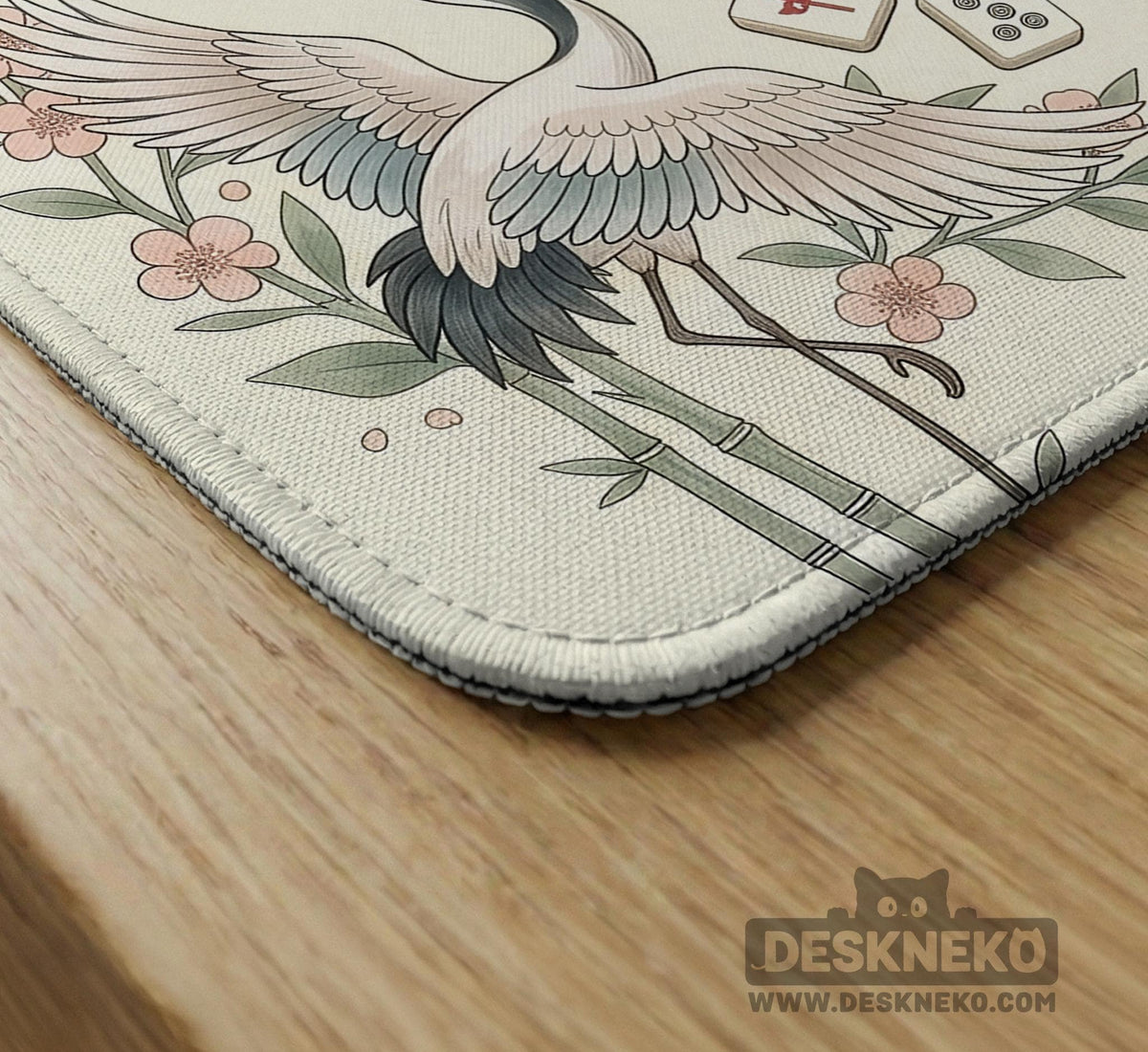 Beige square mahjong mat with a sage border, crane birds, bamboo, flowers, tile icons, and printed rules around a clean center play area.