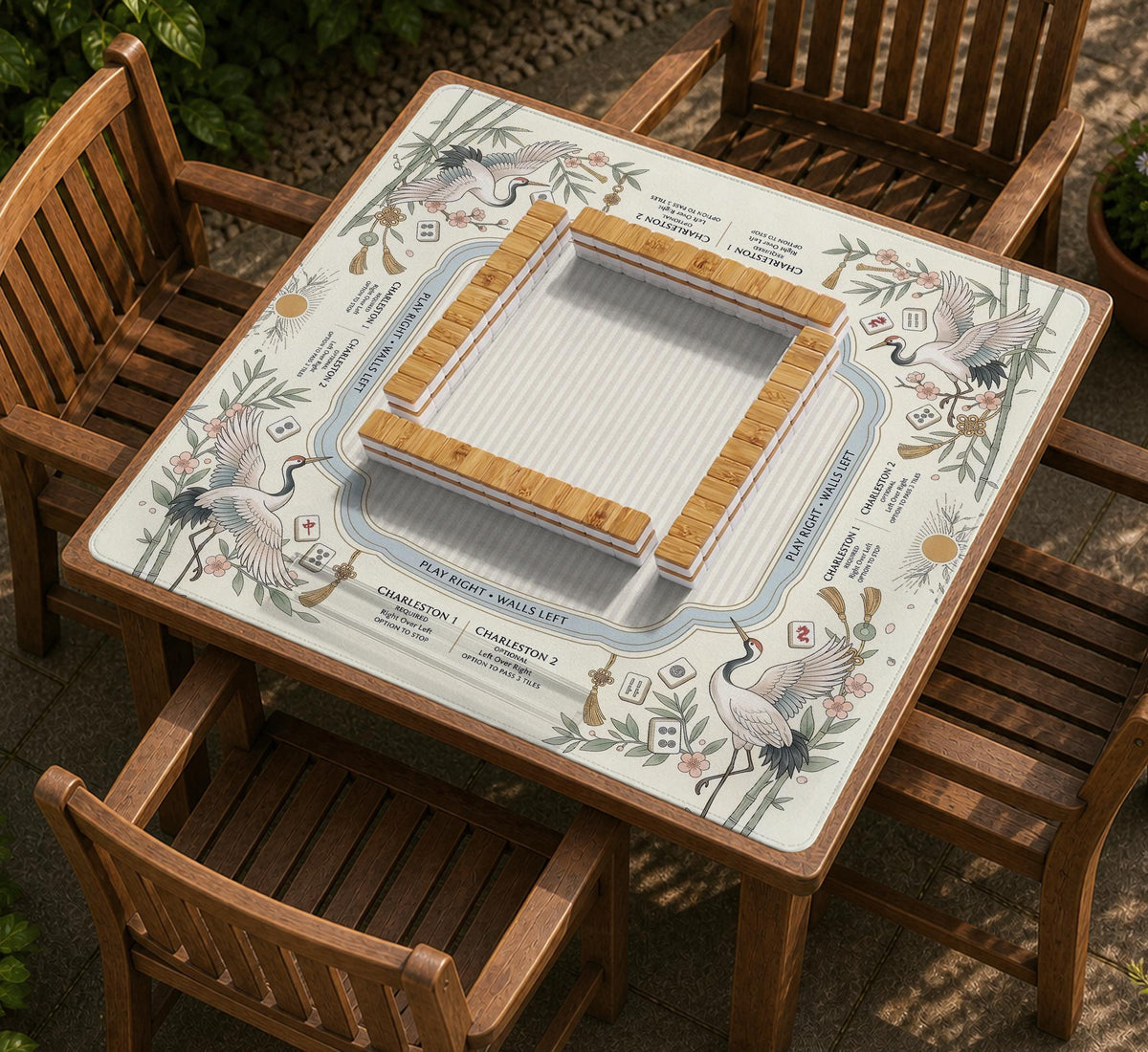 Beige square mahjong mat with a sage border, crane birds, bamboo, flowers, tile icons, and printed rules around a clean center play area.