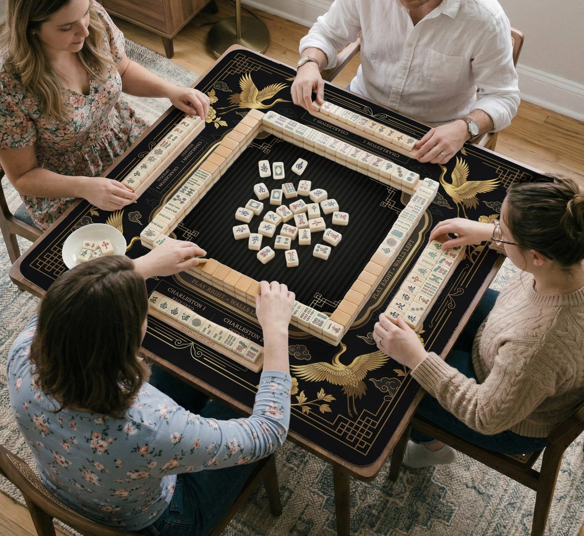 Black and gold square mahjong mat with an art deco crane and floral border, rule reminders around the edges, and a blank center area.