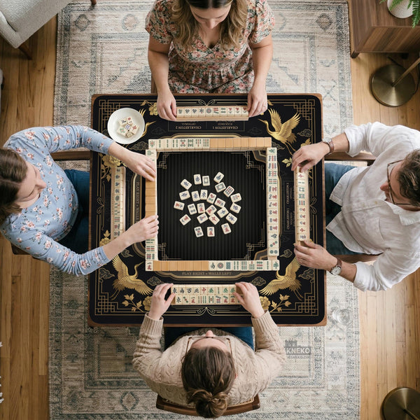 Black and gold square mahjong mat with an art deco crane and floral border, rule reminders around the edges, and a blank center area.