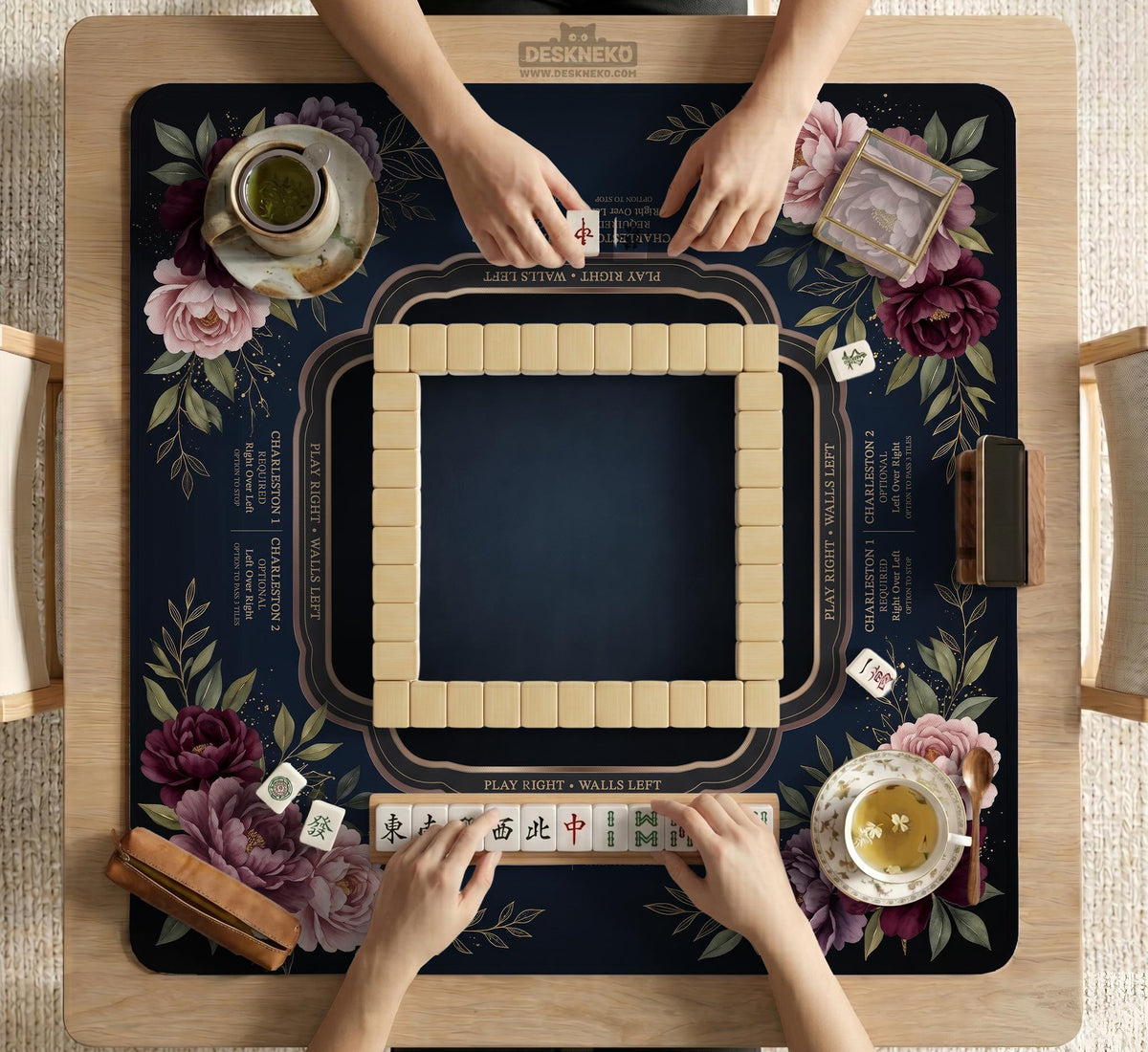 Burgundy mahjong mat with a floral border, gold botanical details, and printed American Mahjong rules on a dark background.