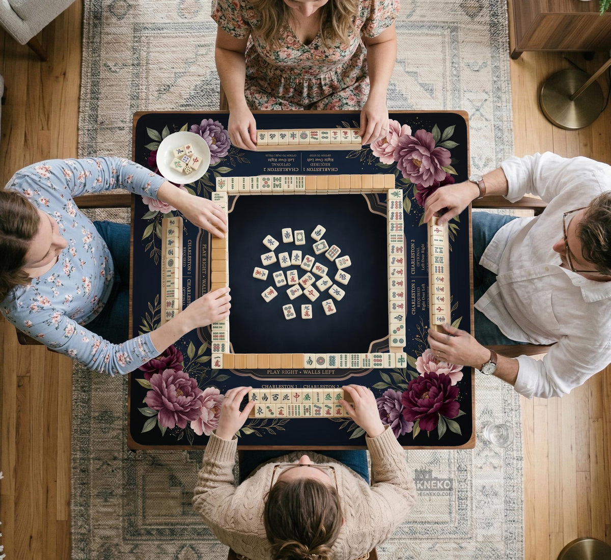 Burgundy mahjong mat with a floral border, gold botanical details, and printed American Mahjong rules on a dark background.