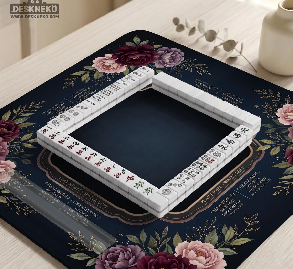 Burgundy mahjong mat with a floral border, gold botanical details, and printed American Mahjong rules on a dark background.