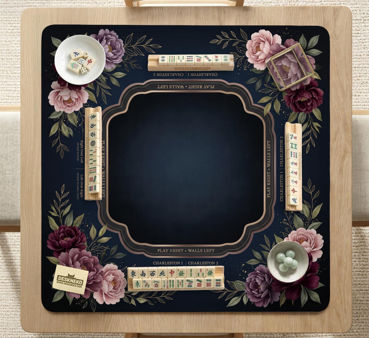 Burgundy mahjong mat with a floral border, gold botanical details, and printed American Mahjong rules on a dark background.