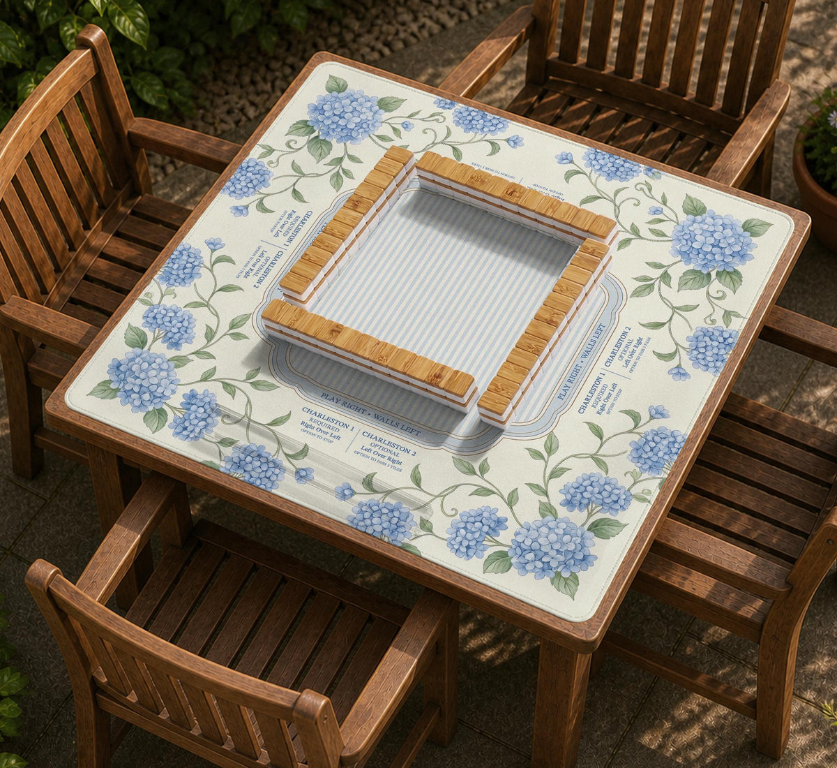 A square mahjong mat with blue hydrangea flowers, green vines, a cream background, a striped center, and printed rules around the border.