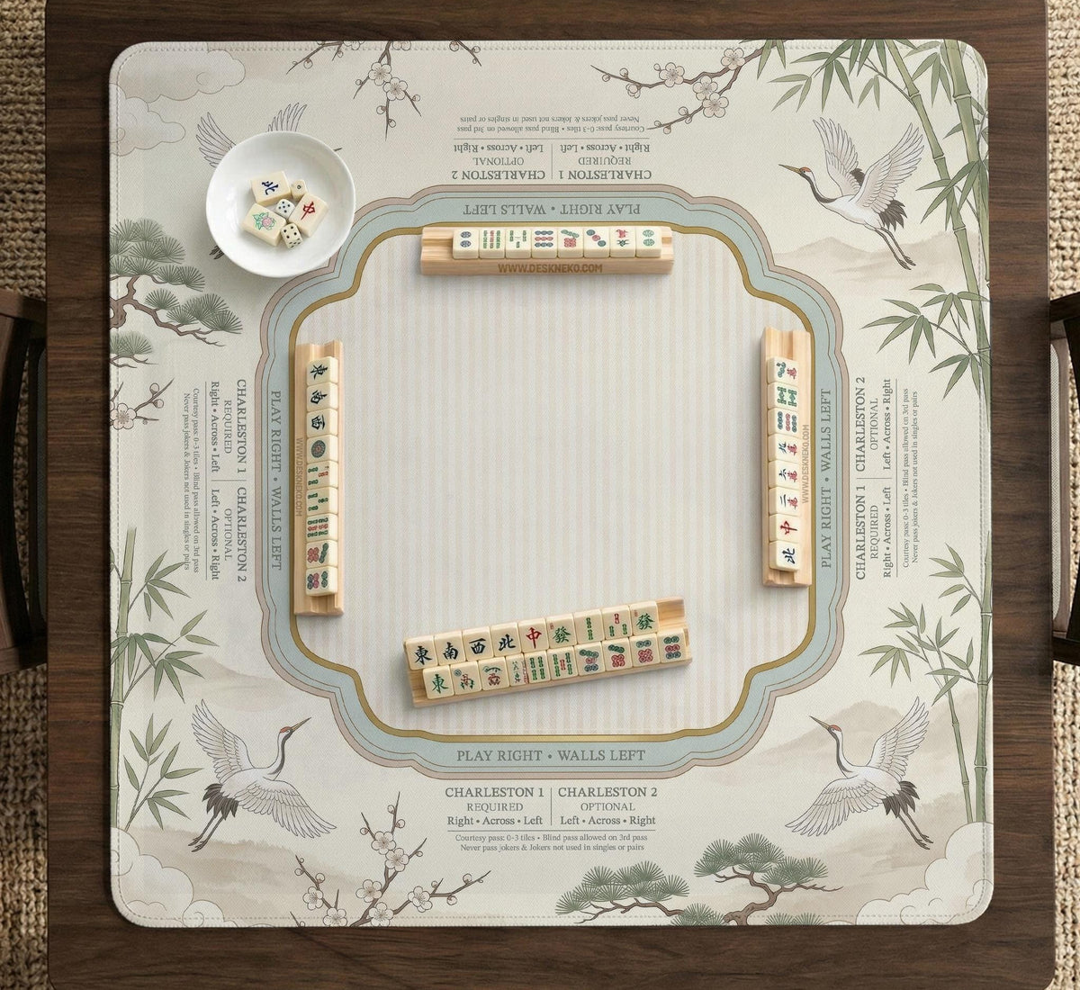 Sage green scalloped mahjong mat with bamboo, crane, and blossom illustration and printed rules around the border.