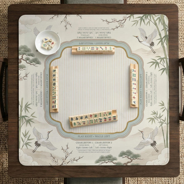 Sage green scalloped mahjong mat with bamboo, crane, and blossom illustration and printed rules around the border.