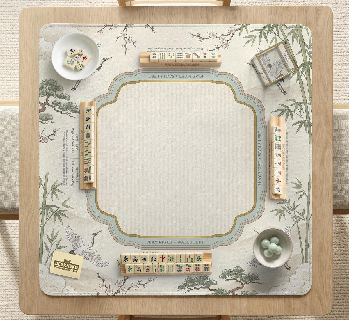 Sage green scalloped mahjong mat with bamboo, crane, and blossom illustration and printed rules around the border.