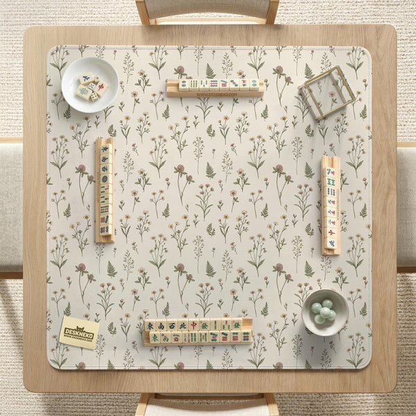 Cream mahjong mat with a floral pattern of small wildflowers and sage leaves, shown with a scalloped edge on a light neutral background.