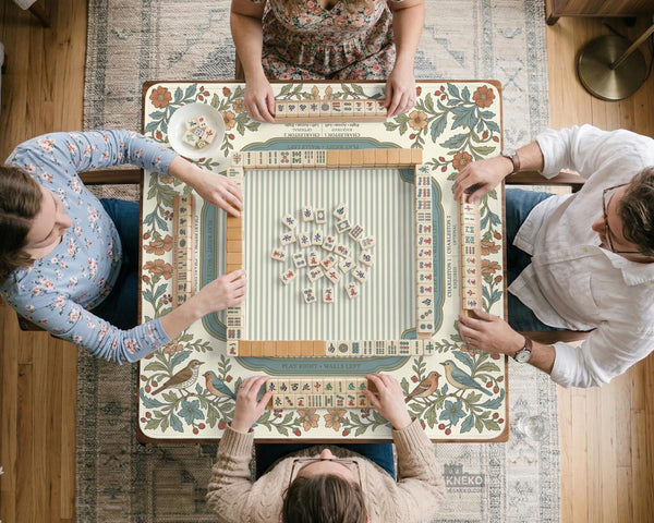 Square mahjong mat with a cream background, blue birds, sage leaves, terracotta flowers, and a decorative botanical border with printed rules text.