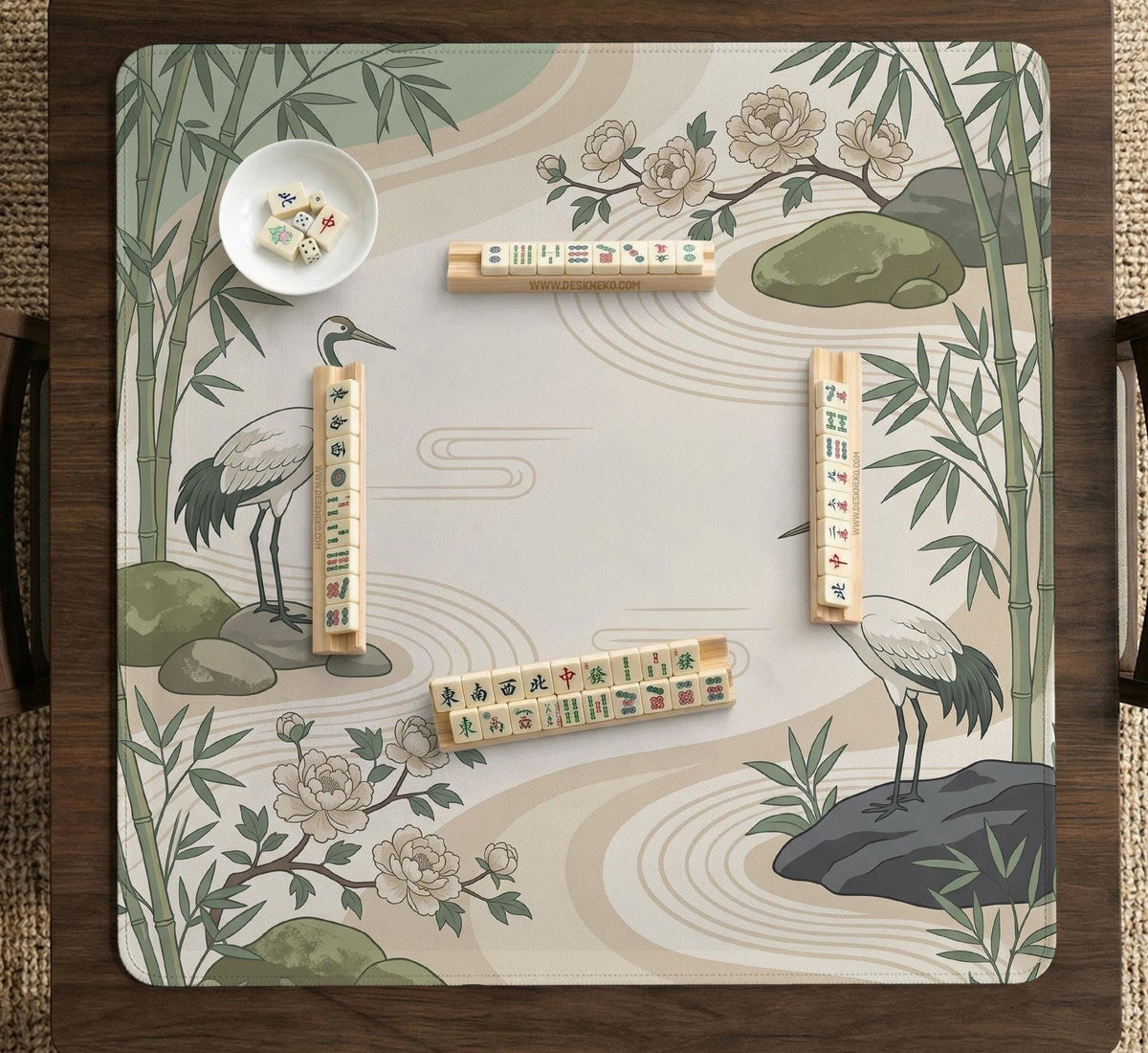 Square mahjong mat with a cream background, sage green cranes, bamboo leaves, peony branches, stones, and thin linework.