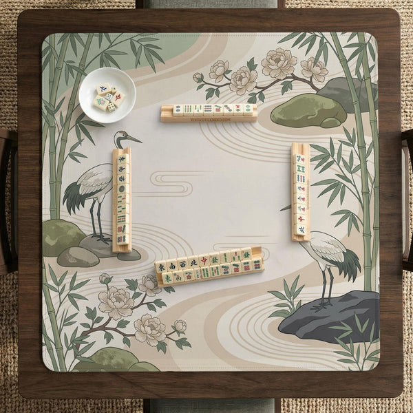 Square mahjong mat with a cream background, sage green cranes, bamboo leaves, peony branches, stones, and thin linework.
