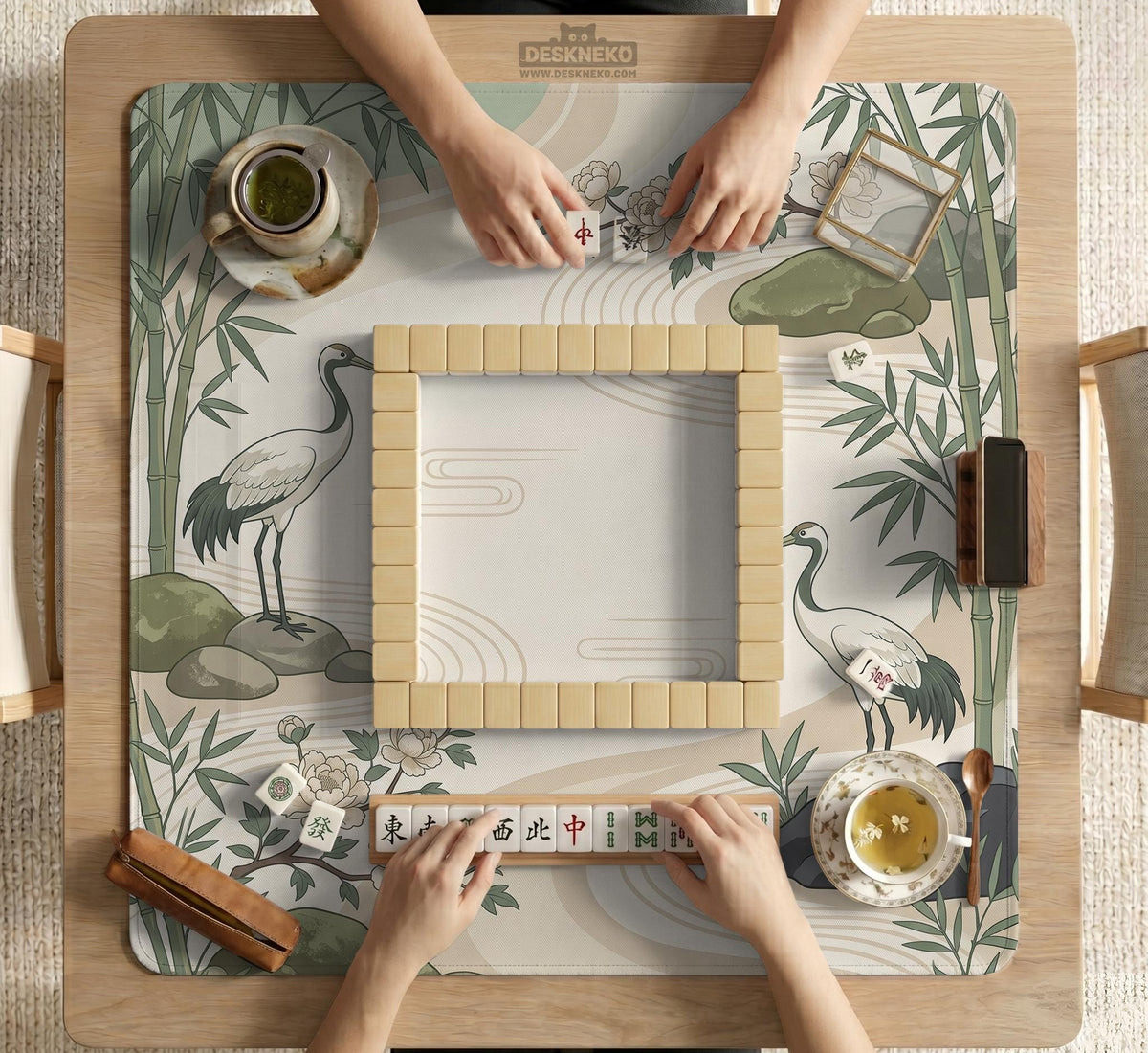 Square mahjong mat with a cream background, sage green cranes, bamboo leaves, peony branches, stones, and thin linework.