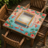 A square mahjong mat with flamingos, hibiscus flowers, palm leaves, and aqua water accents on a coral background with a scalloped edge.