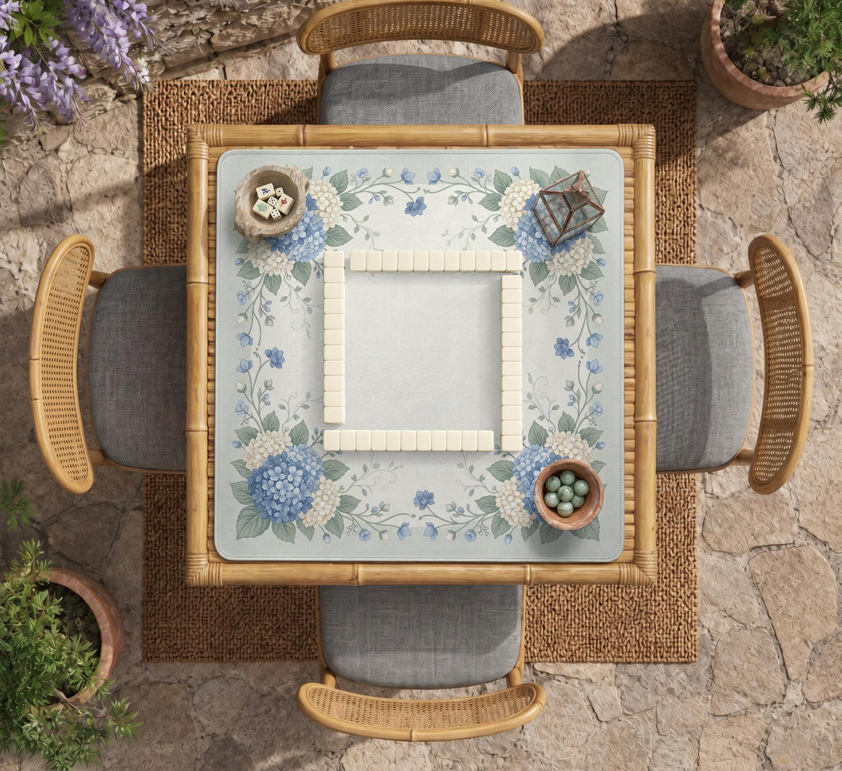A square blue mahjong mat with hydrangea flowers, cream blossoms, sage leaves, and vines around a plain center play area. The edge is scalloped.