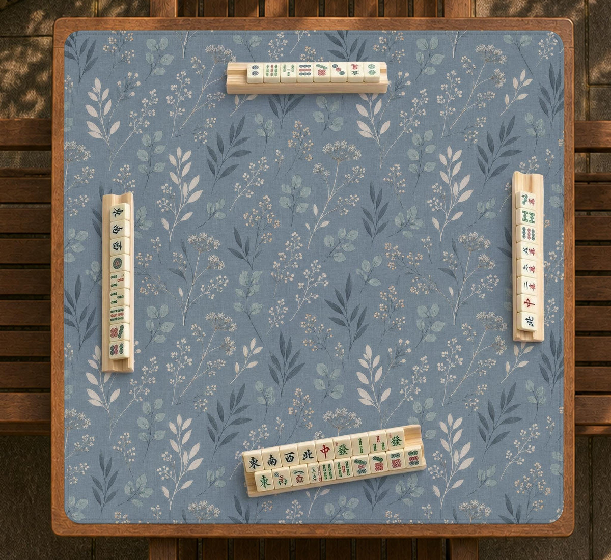 Blue mahjong mat with a dusty linen-look background and small leafy botanical stems in a floral pattern.