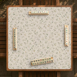 Cream square mahjong mat with a sage vine and leaf botanical pattern and scalloped edges.