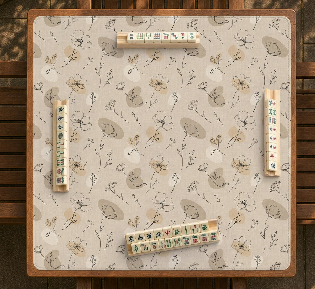 Neutral floral mahjong mat with delicate botanical line art and a scalloped edge on a cream background.